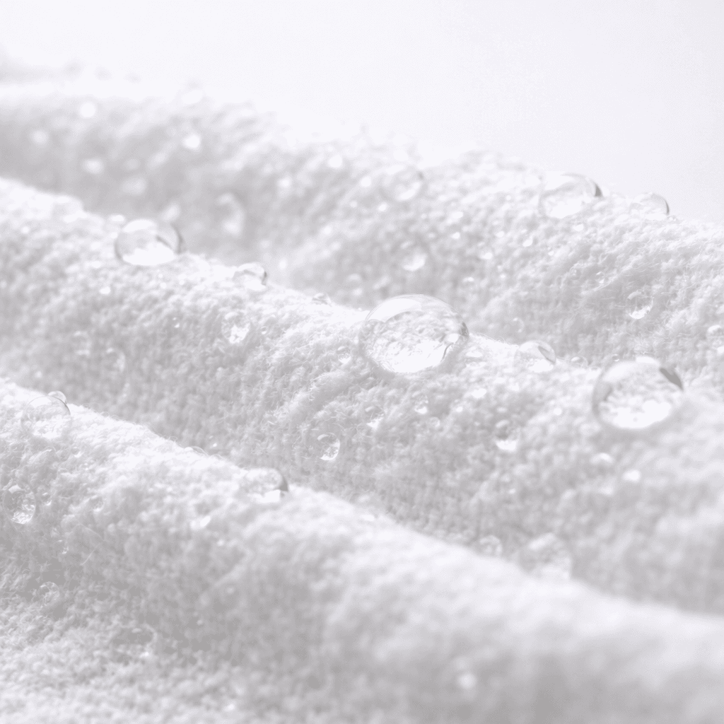 Крупный план текстуры салфетки UNICORN: плотный мягкий спанлейс с каплями воды